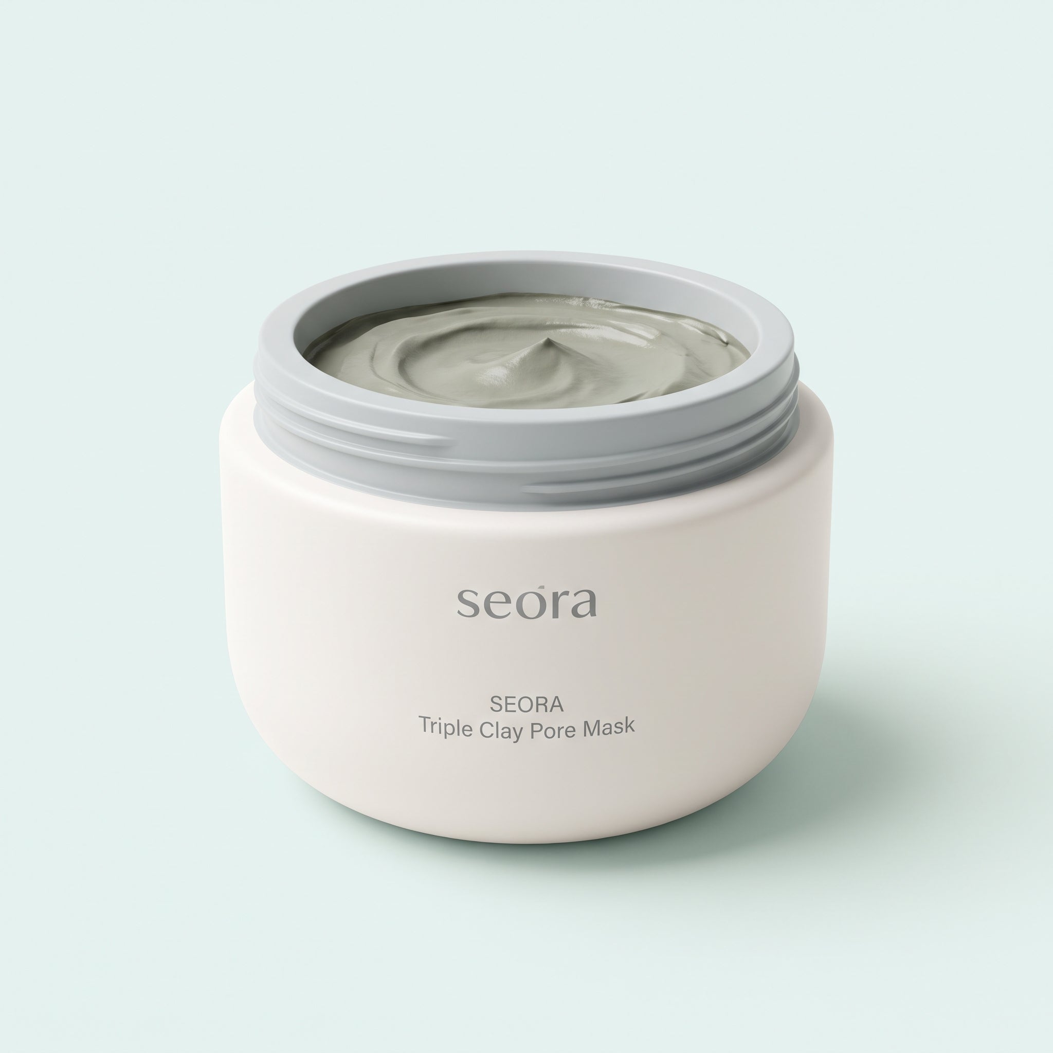 A white cosmetic jar of SEORA Triple Clay Pore Mask with a gray lid, showing the gray mask inside, set against a clean light gray background.